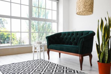 Yeşil kanepeli, çiçekli ve masalı aydınlık oturma odasının içi.