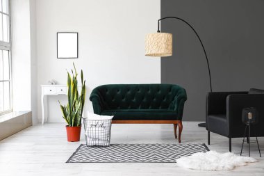 Oturma odasının içinde yeşil kanepe, ayakta duran lamba ve koltuk.