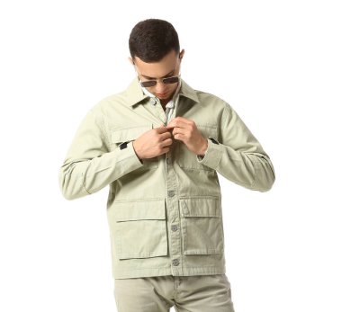 Beyaz arka planda güneş gözlüklü ve ceketli genç adam.