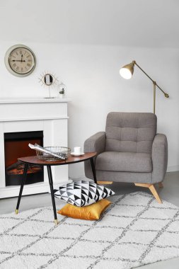 Yumuşak koltuklu, masalı ve modern şömineli, aydınlık oturma odasının içi.