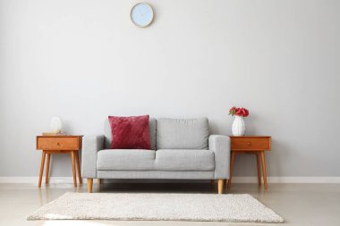 Ahşap komodinli şık bir iç mekan ve açık gri duvarın yanındaki kanepe.