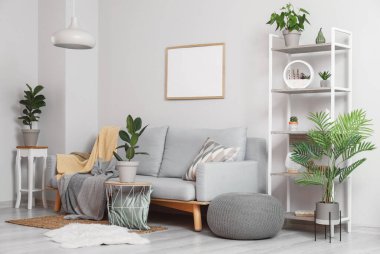 Kanepesi, boş fotoğraf çerçevesi ve çiçekleri olan modern oturma odası.