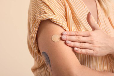 Renkli arka planda uygulamalı nikotin bandı olan olgun bir kadın, yakın plan. Sigara içmeyi bırakma