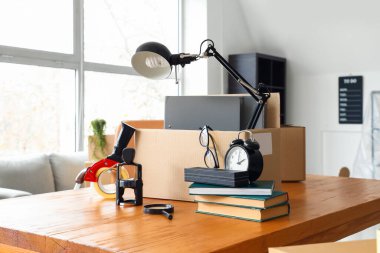 Taşındığı gün masada üzerinde eşyalar ve koli bandı olan karton kutular.