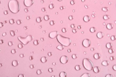 Pembe arkaplanda su damlaları, yakın plan.