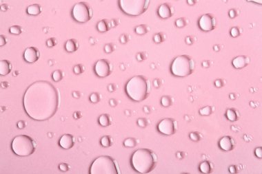 Pembe arkaplanda su damlaları, yakın plan.