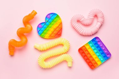 Renkli pop tüpleri ve patlayan oyuncaklar pembe arka planda