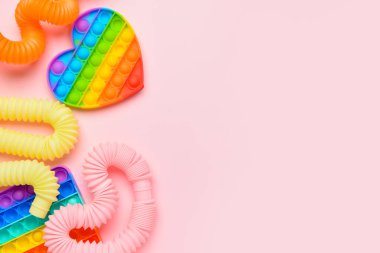 Renkli pop tüpleri ve patlayan oyuncaklar pembe arka planda
