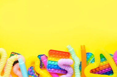 Renkli pop tüpleri ve patlayan oyuncaklar sarı arka planda