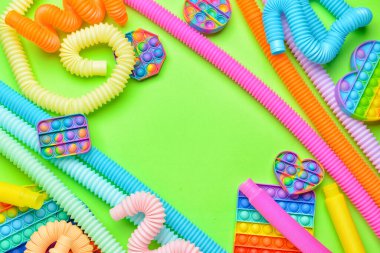 Renkli pop tüplerinden yapılmış çerçeve ve yeşil arka planda hareketli oyuncaklar