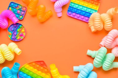 Renkli pop tüplerinden yapılmış çerçeve ve turuncu arka planda hareketli oyuncaklar