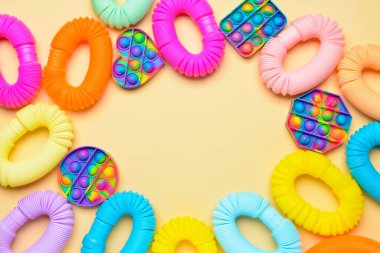 Renkli pop tüplerinden yapılmış çerçeve ve sarı arka planda hareketli oyuncaklar