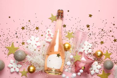 Güzel bir Noel kompozisyonu dekor ve pembe arka planda bir şişe şampanya.
