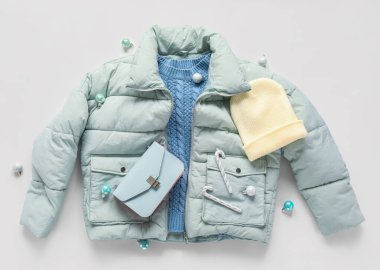 Şık bir ceket, süveter, aksesuarlar ve arka planda Noel dekoru.