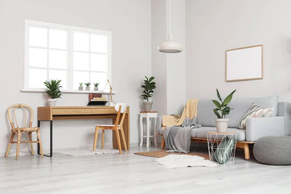 Interior of modern living room with sofa, workplace and houseplants