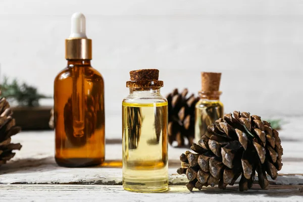 Bottles Essential Oil Pine Cones Light Wooden Background Closeup — Fotografia de Stock