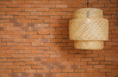 Hasır lamba tuğla duvarın yanında asılı.