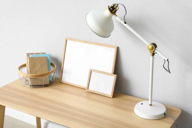 Beyaz lamba, kitaplar ve ışık duvarının yanındaki çerçeveli masa.