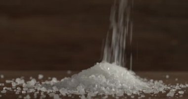 Ahşap yüzeye deniz tuzu dökülüyor, yakın plan.