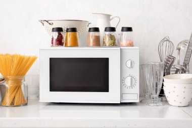 Modern mikrodalga fırın ve mutfak aletleri ışık duvarının yanında.
