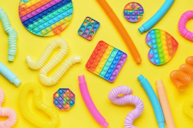 Renkli pop tüpleri ve patlayan oyuncaklar sarı arka planda