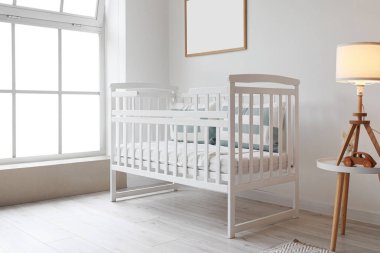 Çocuk odasındaki büyük pencerenin yanında rahat bir beşik.