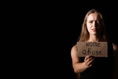 Elinde kâğıt olan korkmuş bir kadın. Koyu arkaplanlı, eve gelen bir mesaj. Şiddet kavramı
