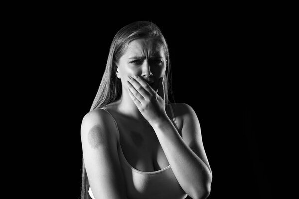 Scared woman with bruises on dark background. Violence concept
