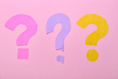 Pembe arka planda kağıttan yapılmış soru işaretleri