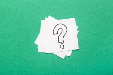 Yeşil arkaplanda soru işareti olan beyaz yapışkan notlar