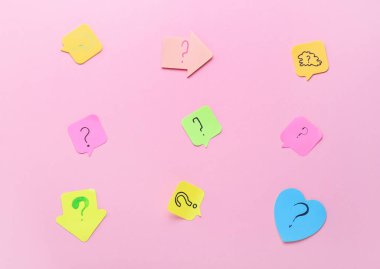 Pembe arka planda soru işaretleri olan yapışkan notlar