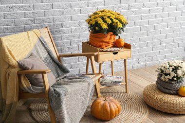 Rahat koltuk ve kasımpatı çiçekleri, içerideki gri tuğla duvarın yanında.