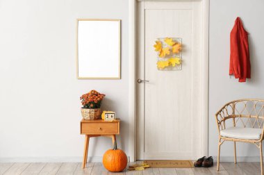 İçinde güzel kasımpatı çiçekleri ve ışık duvarında boş fotoğraf çerçevesi olan bir oda.