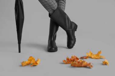 Gri arka planda bayan bacaklar ve şemsiye, yakın plan.