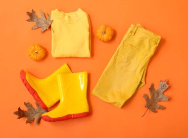 Çocuk kıyafetleri, çizmeler ve arka planda sonbahar dekoru.