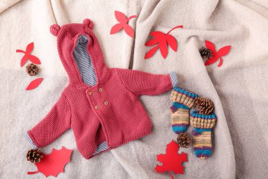 Güzel bebek süveteri, çoraplar ve kumaş arka planda sonbahar dekoru.