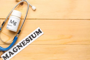 Stetoskop, ilaç şişesi ve tahta arka planda kelime MAGNESIUM