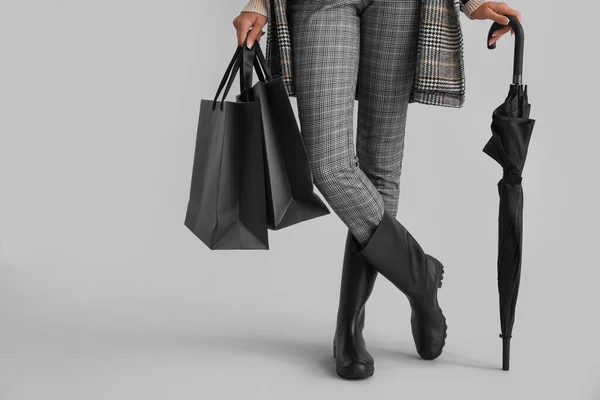 グレーの背景にショッピングバッグや傘を持つエレガントな女性は クローズアップ — ストック写真