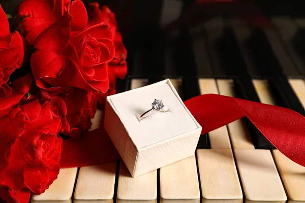 Krabička Stříbrným Zásnubním Prstenem Červenou Stuhou Růžemi Klavírních Klávesách Detailní — Stock fotografie