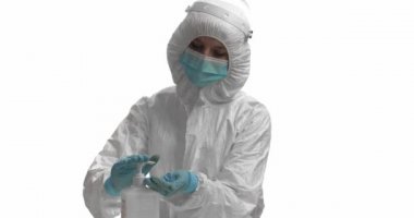 Koruyucu kıyafetli doktor beyaz arka planda elleri dezenfekte ediyor.