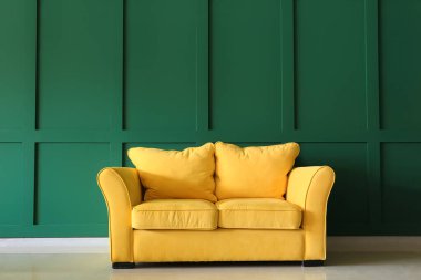 Yeşil duvarın yanındaki rahat sarı kanepe