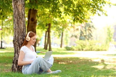 Parkta müzik dinleyen güzel bir genç kadın.