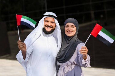Geleneksel giyinmiş bir çift ve BAE 'nin ulusal bayrakları açık havada