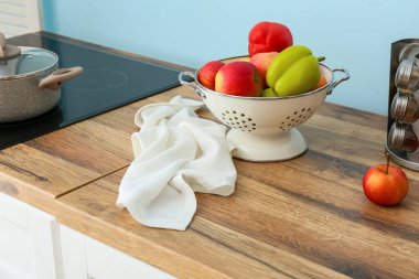 Mavi duvarın yanındaki ahşap masanın üzerinde yiyecek ve peçeteli Colander.