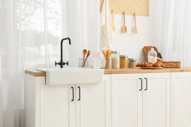 Beyaz tezgahlı, lavabolu ve yiyecekli bir mutfak.