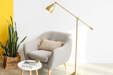 Altın lamba, koltuk ve ışık duvarının yanındaki masa.