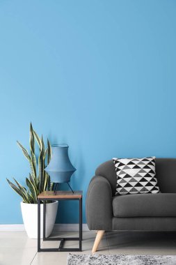 Masada şık bir lamba, çiçek ve mavi duvarın yanındaki kanepe.