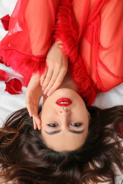 Yatakta gül yapraklarıyla kaplı seksi genç bir kadın. Sevgililer Günü kutlaması