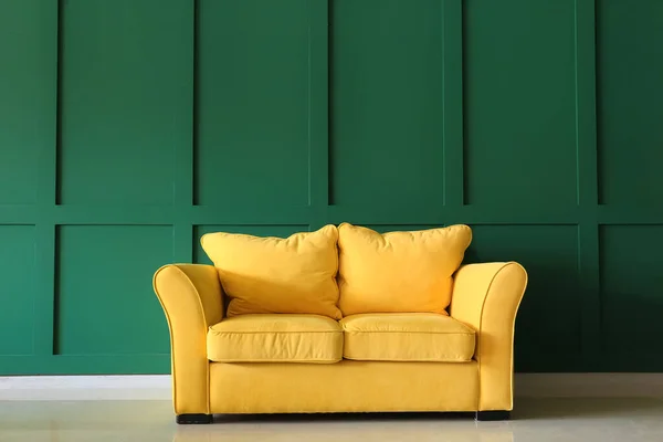 Cozy yellow couch near green wall