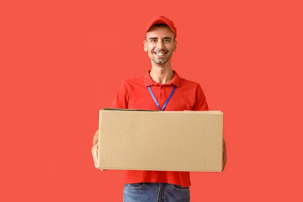 Männlicher Kurier Mit Paket Auf Farbigem Hintergrund — Stockfoto